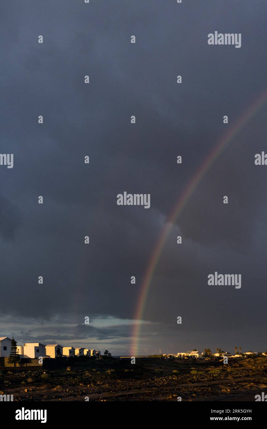 Kanarische Inseln, Lanzarote, Montana Roja: Ein doppelter Regenbogen erleuchtet den Himmel über einigen neuen Gebäuden in der Region Montana Roja Stockfoto