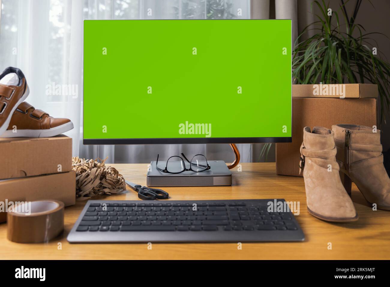 Online Schuhgeschäft Mockup, Computermonitor mit leerem grünem Bildschirm auf dem Schreibtisch zu Hause. KMU-Unternehmen Stockfoto