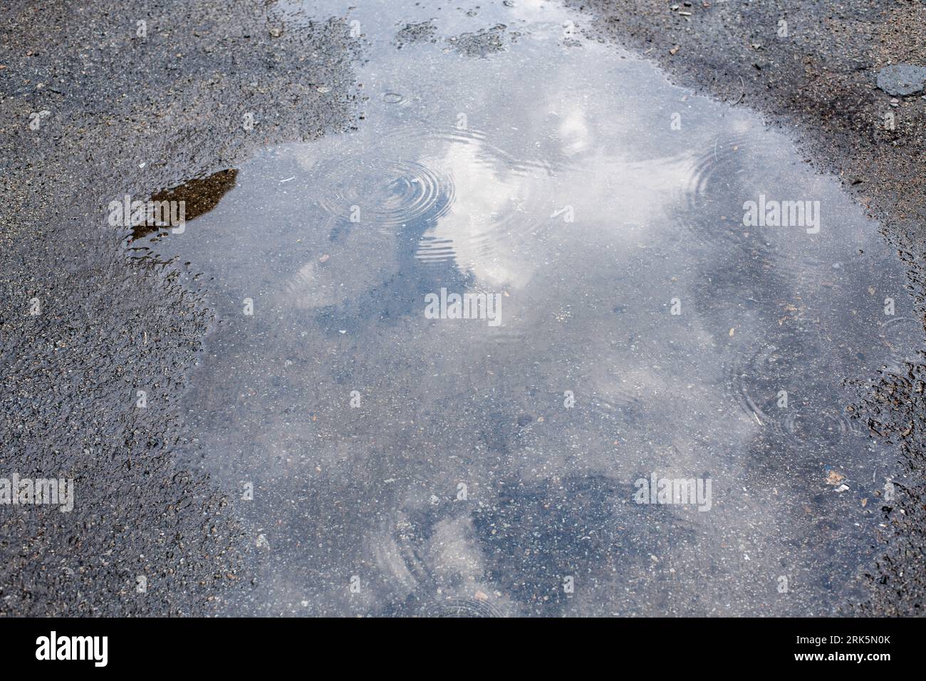 Reflection of sky sun clouds in Puddle. After rain Stockfoto