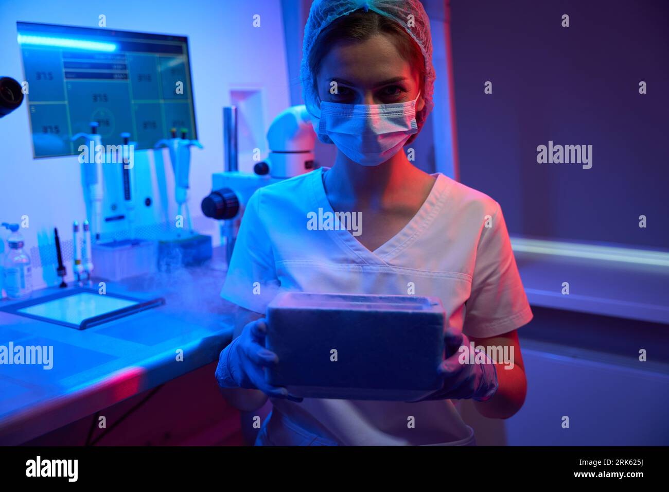 Die Laborassistentin des Embryologen hält einen Tank mit flüssigem Stickstoff in den Händen Stockfoto