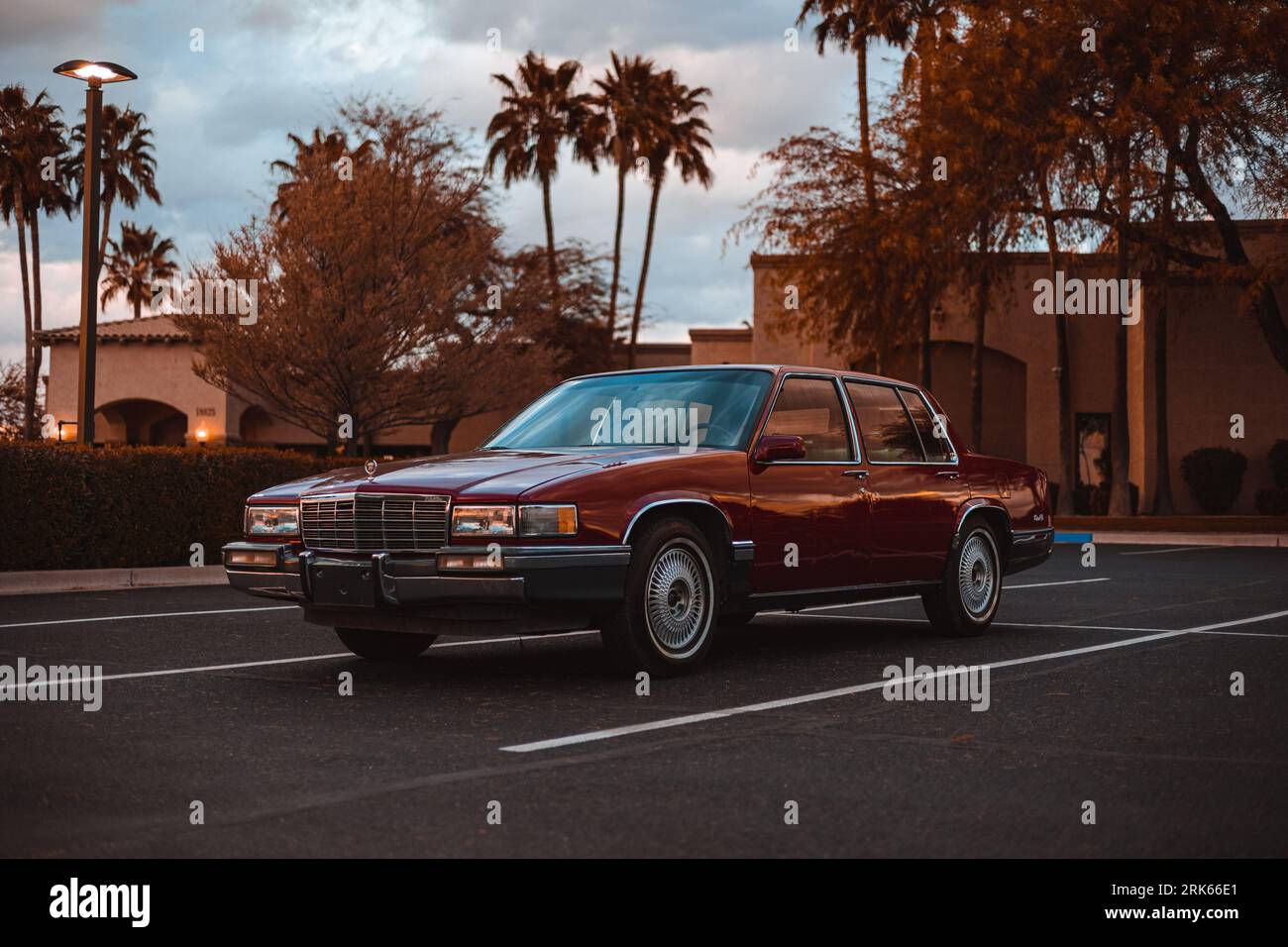 Eine klassische rote Cadillac-Limousine aus dem Jahr 1991, die in einer malerischen Umgebung vor grünen Bäumen geparkt ist Stockfoto