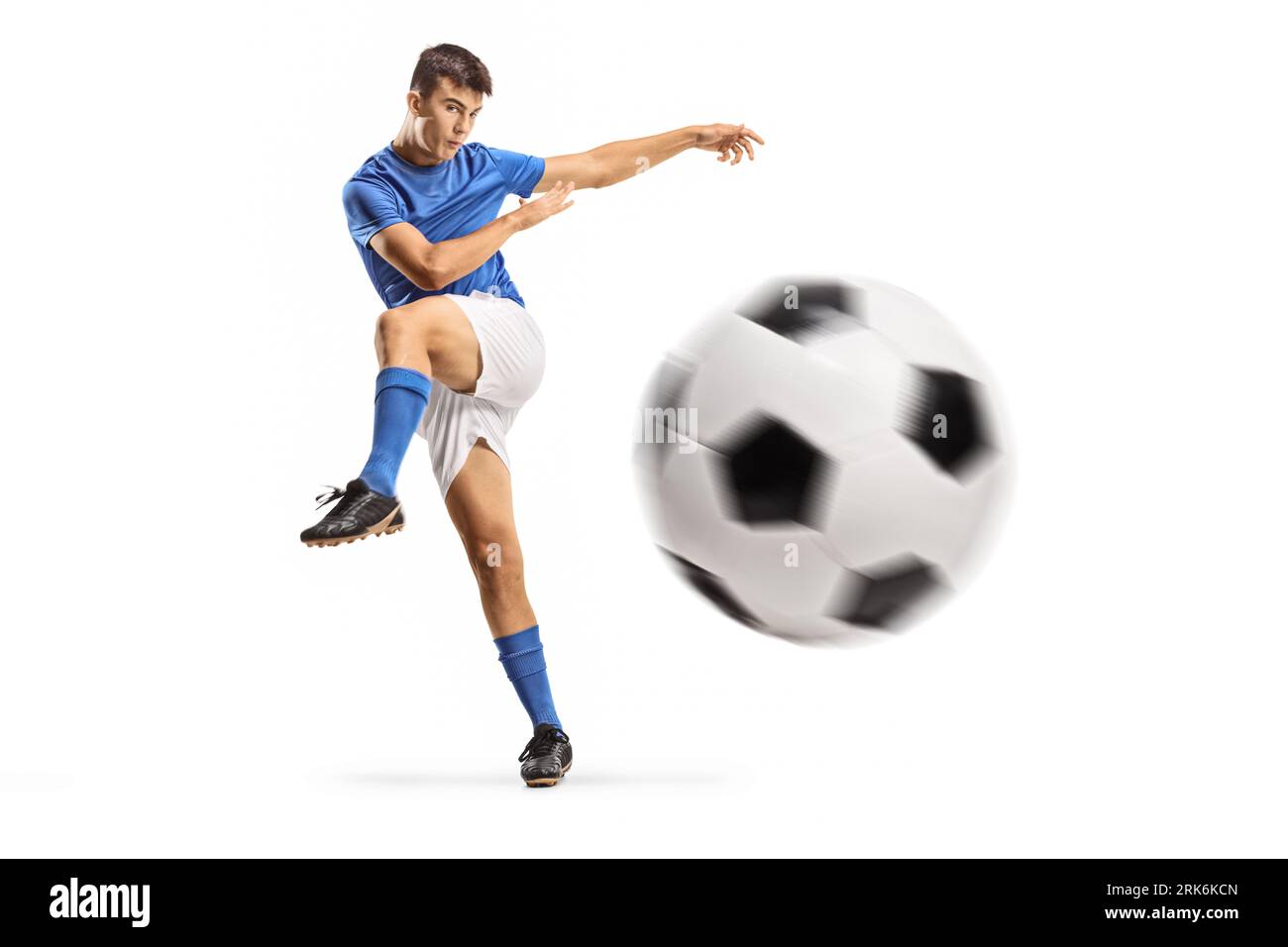 Junger Fußballspieler tritt einen Ball isoliert auf weißem Hintergrund Stockfoto