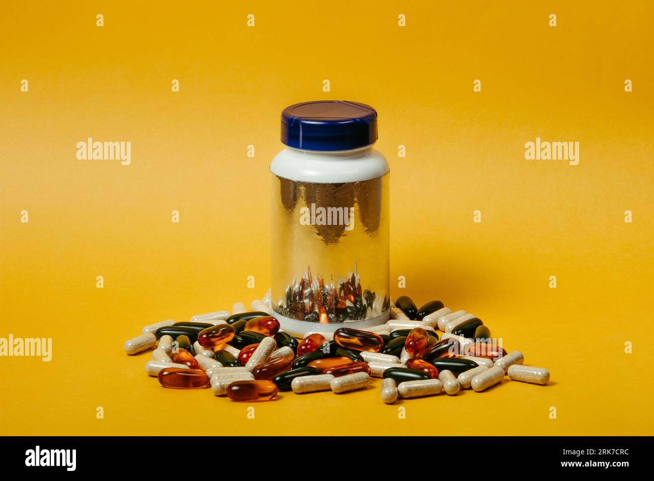 Ein Glas, das mit Vitaminergänzungskapseln auf gelbem Hintergrund gefüllt ist Stockfoto
