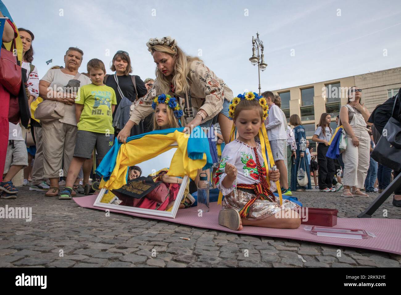 Berlin, Deutschland. August 2023. Am 24. August 2023 versammelten sich Ukrainer am Brandenburger Tor in Berlin, um den Unabhängigkeitstag der Ukraine zu begehen. Aber das war keine gewöhnliche Feier. Die Menge, ein Meer von Sonnenblumen, Fahnen, Fahnen und traditioneller ukrainischer Kleidung, kam mit einer Botschaft der Erinnerung und Belastbarkeit. In einer symbolischen Geste hielten die Teilnehmer Spiegel hoch, insgesamt 503, die jeweils das Gesicht eines Kindes widerspiegeln, das im russischen Krieg gegen die Ukraine verloren ging. Die Spiegel funkelten unter der untergehenden Sonne und dienten als eindringliche Erinnerung an die 503 ukrainischen Kinder, deren Leben abrupt und rücksichtslos war Stockfoto