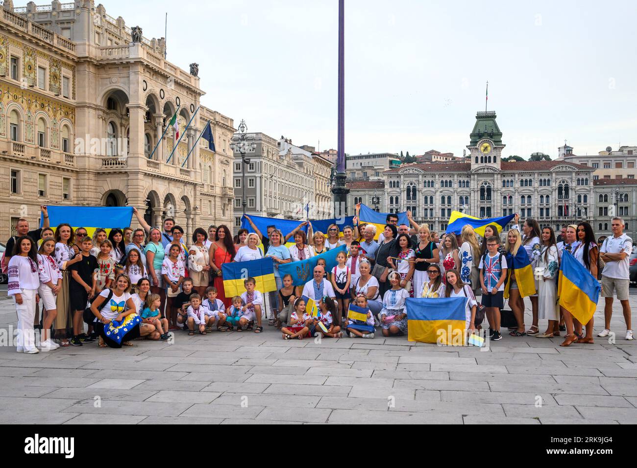 Triest, Italien. August 2023. Ukrainische Bewohner zeigen ihre Nationalflaggen, während sie den 32. Unabhängigkeitstag der Ukraine im Hafen von Triest an der Adria, Italien, begehen. Die Demonstration auf der zentralen Piazza Unità d'Italia war Teil einer "Kette der Einheit", die von ukrainischen Gemeinschaften weltweit organisiert wurde, um ihre Widerstandsfähigkeit, würde und Unterstützung für ihr Land zu demonstrieren, das vor genau 18 Monaten von Russland überfallen wurde. Quelle: Enrique Shore/Alamy Live News Stockfoto