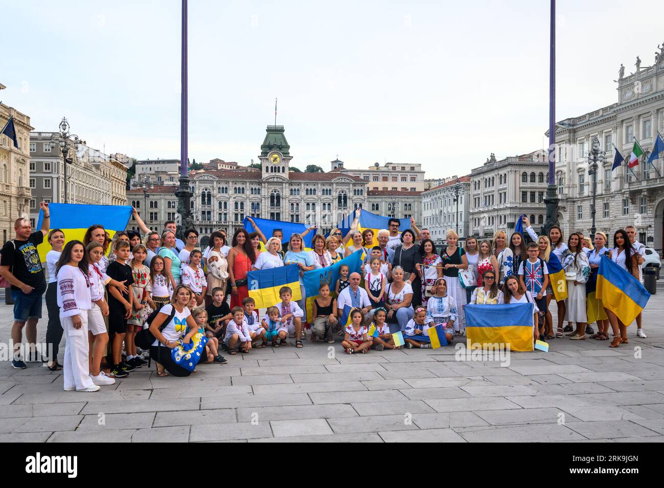 Triest, Italien. August 2023. Ukrainische Bewohner zeigen ihre Nationalflaggen, während sie den 32. Unabhängigkeitstag der Ukraine im Hafen von Triest an der Adria, Italien, begehen. Die Demonstration auf der zentralen Piazza Unità d'Italia war Teil einer "Kette der Einheit", die von ukrainischen Gemeinschaften weltweit organisiert wurde, um ihre Widerstandsfähigkeit, würde und Unterstützung für ihr Land zu demonstrieren, das vor genau 18 Monaten von Russland überfallen wurde. Quelle: Enrique Shore/Alamy Live News Stockfoto