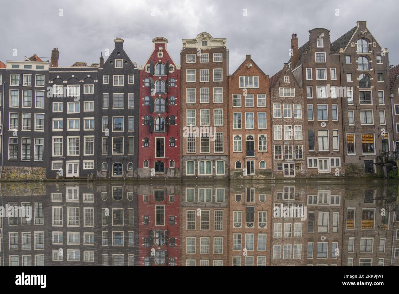 Stadtgebäude von Amsterdam neben den Kanälen in den Niederlanden mit farbenfrohen Fassaden, historischen Giebeln und klassischen holländischen Stadthäusern. Stockfoto