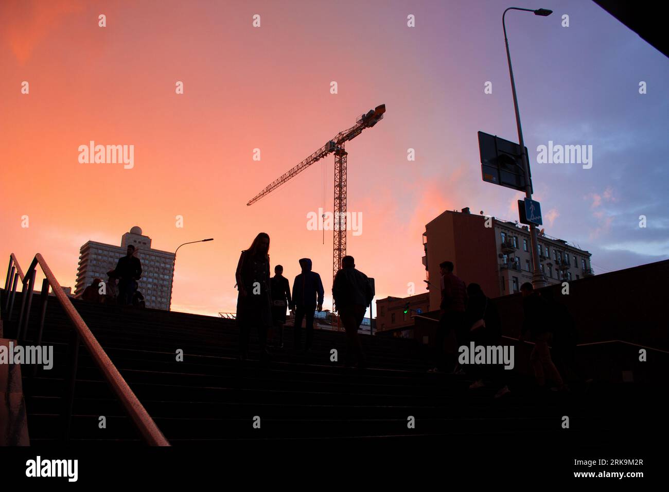 : Ein beschaulicher Sonnenuntergang nach dem Regen färbt die Stadt in goldenen Tönen. Vor dem Hintergrund von Arbats legendärem Sowjet steigen Pendler in die Metro ab Stockfoto