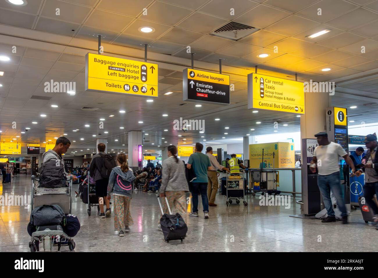 Gelbe Schilder an der Decke geben den Passagieren eine Wegbeschreibung bei Ankunft am London Heathrow Airport Terminal 3 Stockfoto