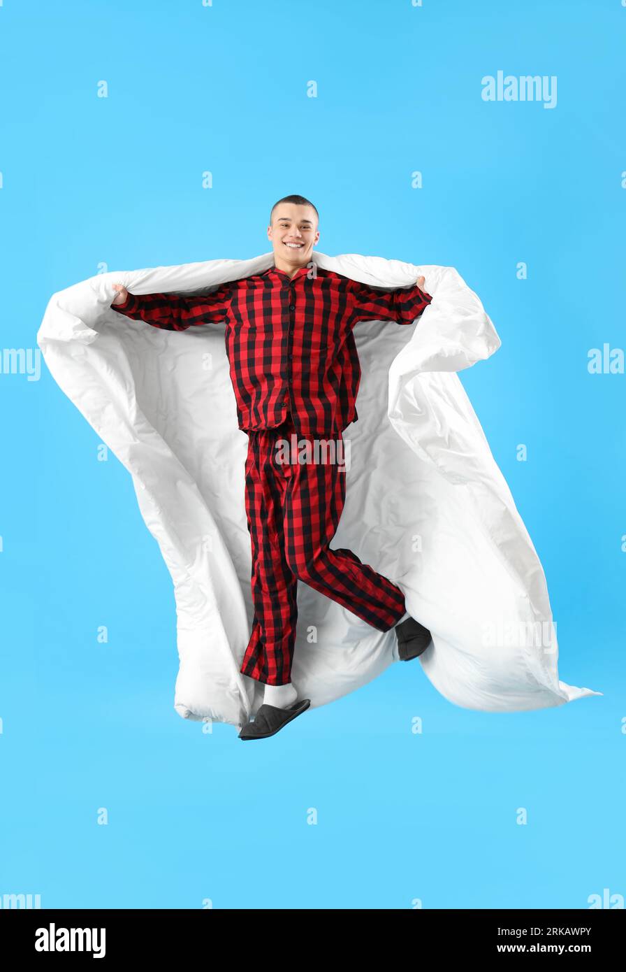 Springender junger Mann mit Decke auf blauem Hintergrund Stockfoto