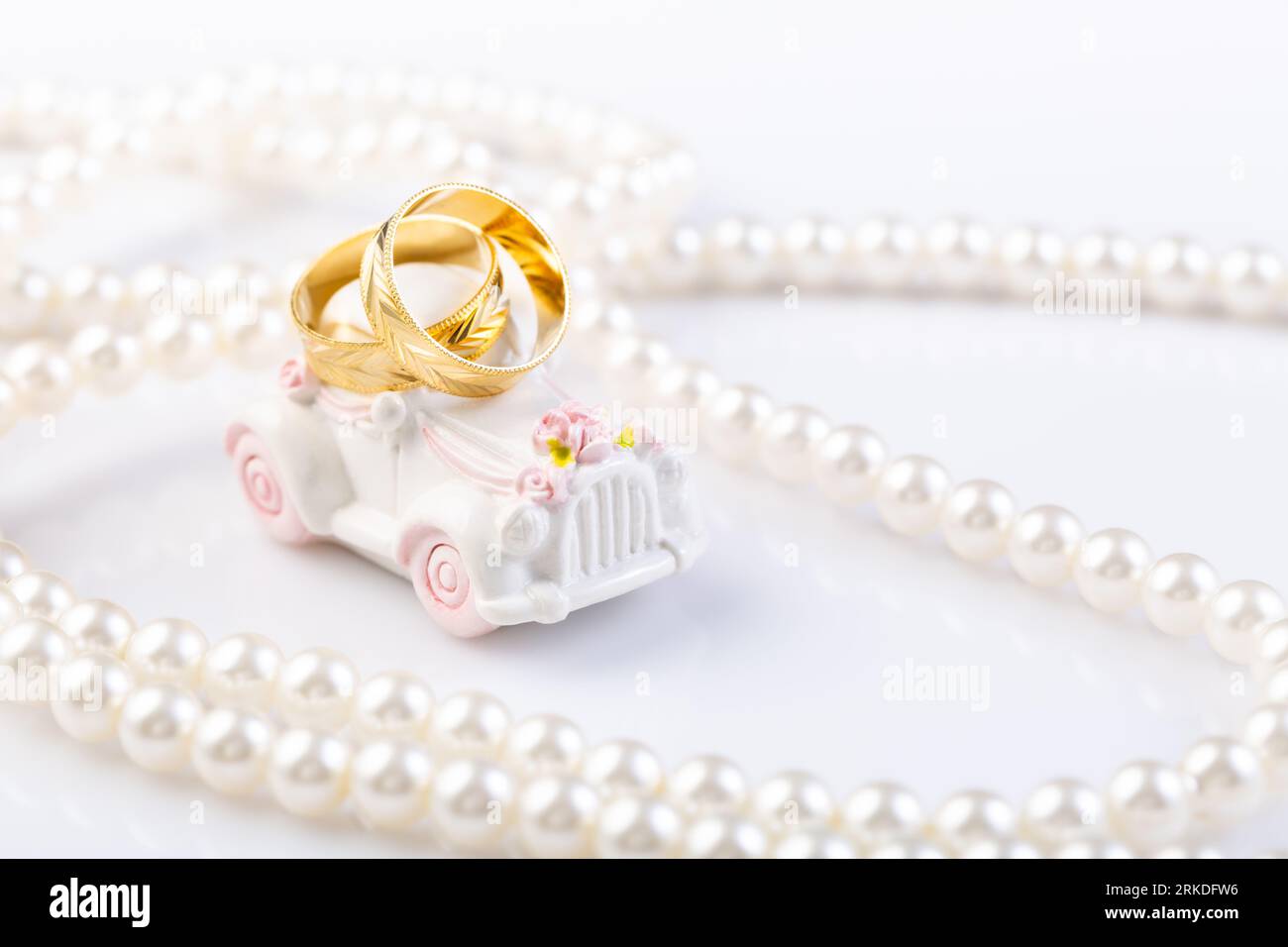 Zwei Eheringe auf einem kleinen Oldtimer mit Perlenkette. Stockfoto