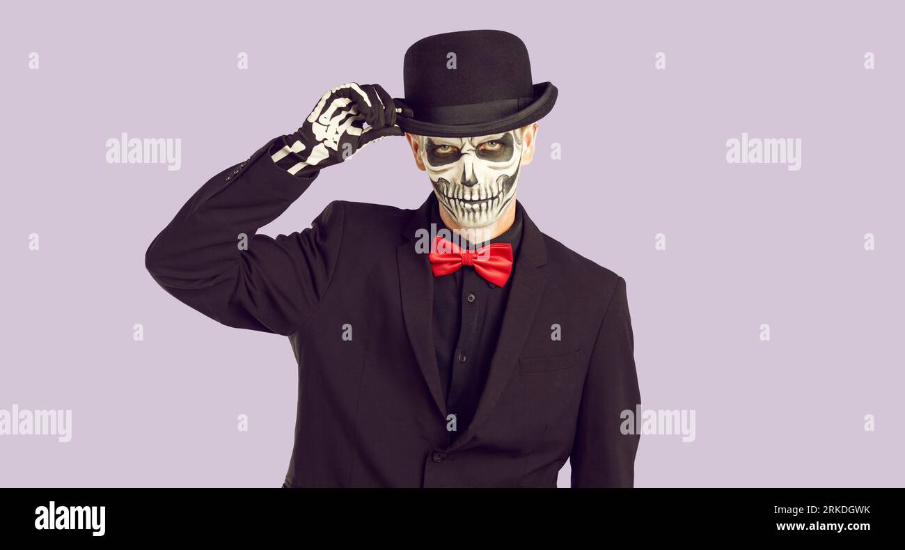 Gutaussehender Mann mit Skelett-Make-up, der seinen Hut berührt Stockfoto