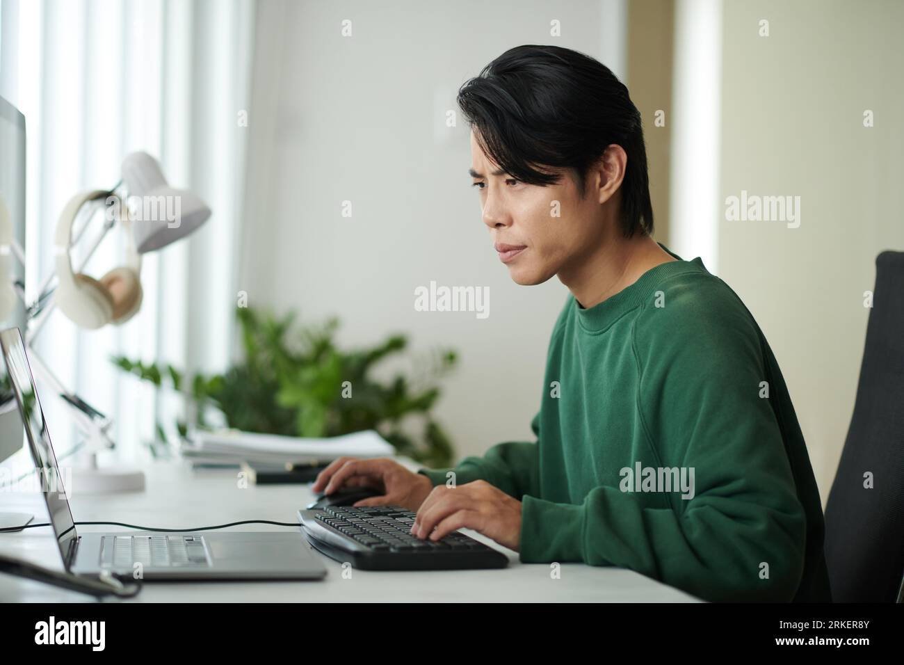 Nachdenklicher junger Softwareentwickler, der sich den Laptop-Bildschirm anschaut und den Programmiercode auf Fehler überprüft Stockfoto