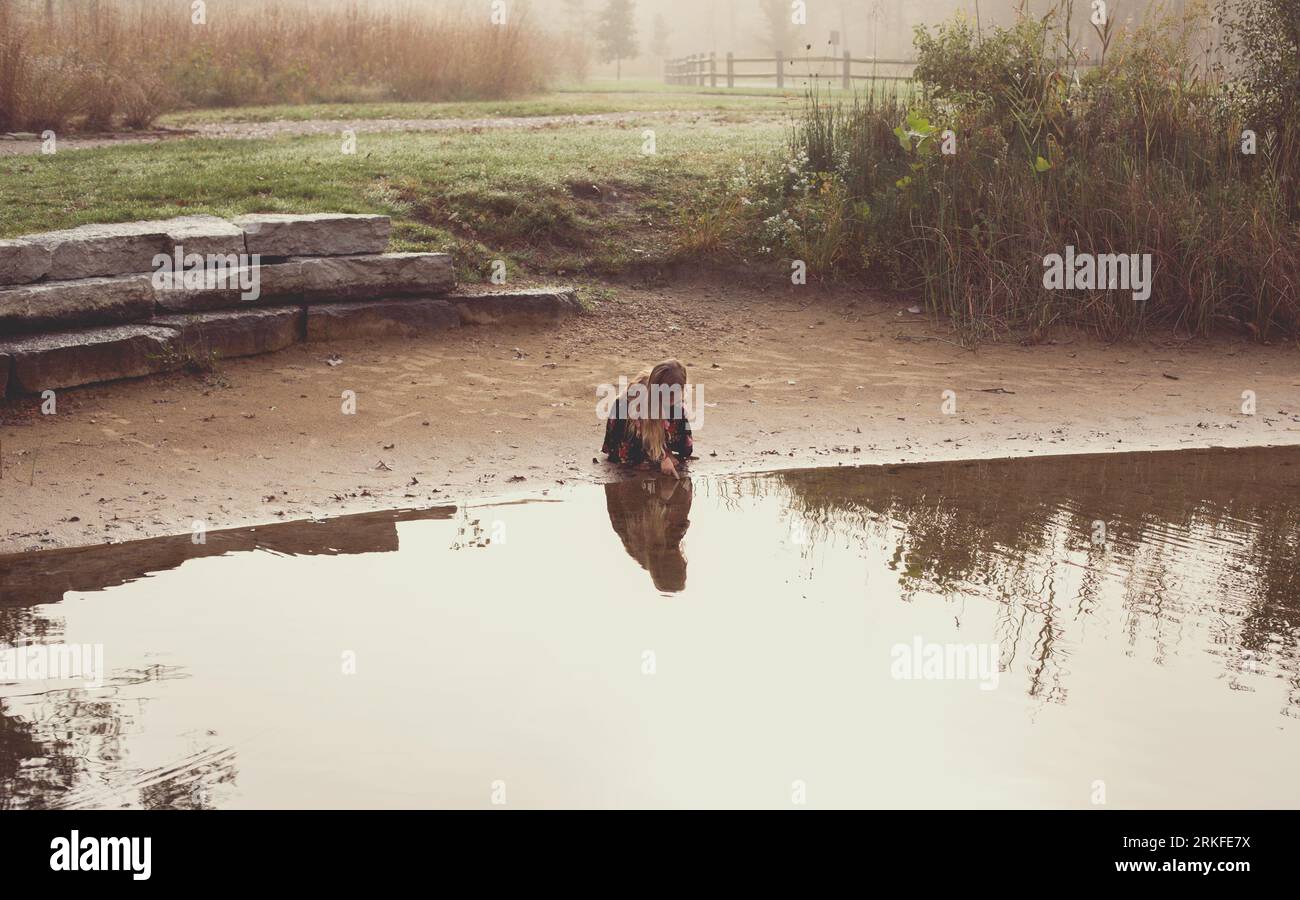 Ein kleines Mädchen, ganz allein im Morgennebel am See Stockfoto