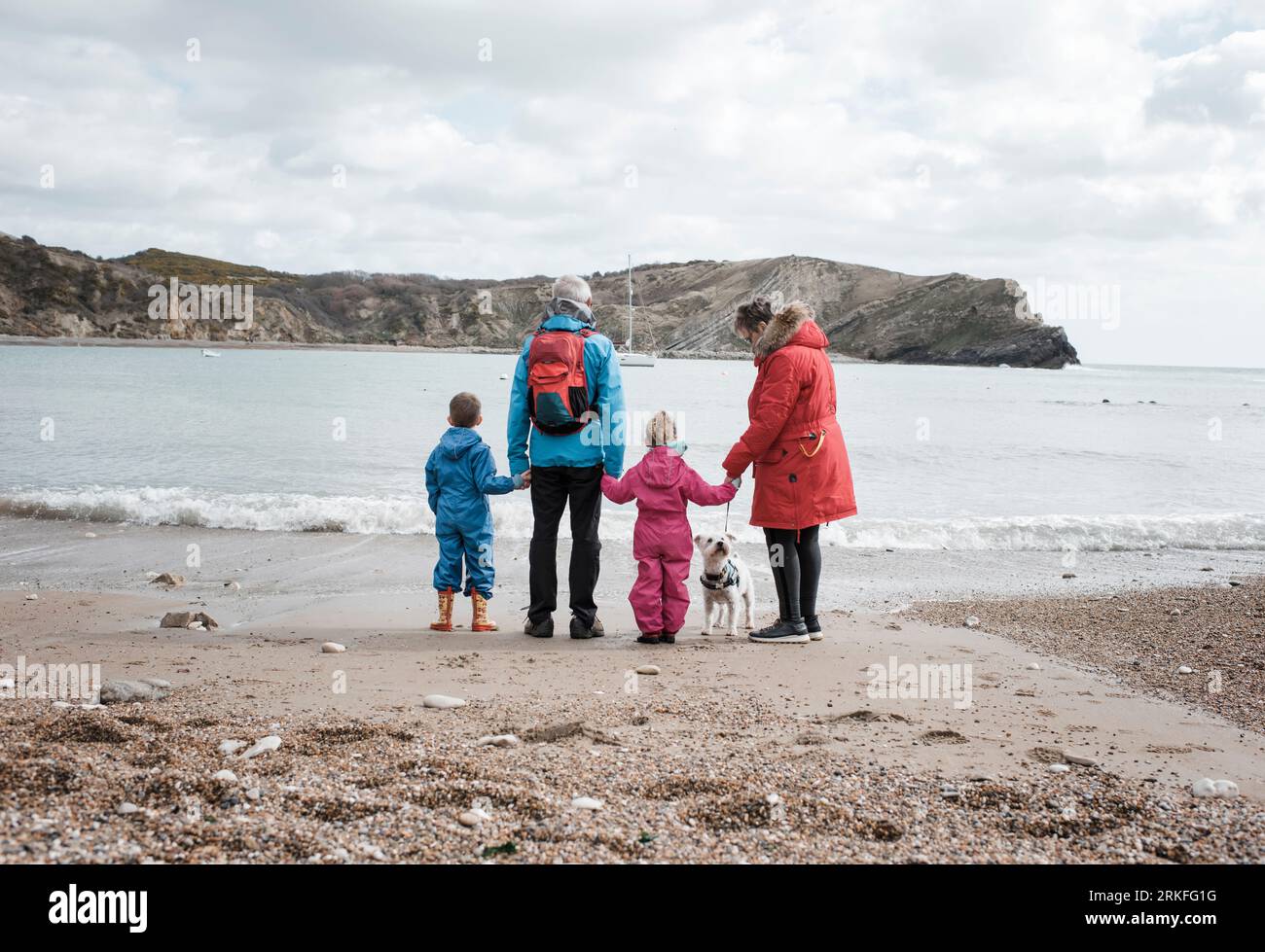 Großeltern stehen am Strand mit Enkelkindern im lulworth Cove Stockfoto