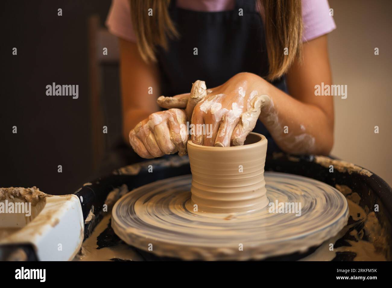 Nahaufnahme der Hände eines Teenagers, die Töpferwaren auf einem Töpfchen modellieren Stockfoto