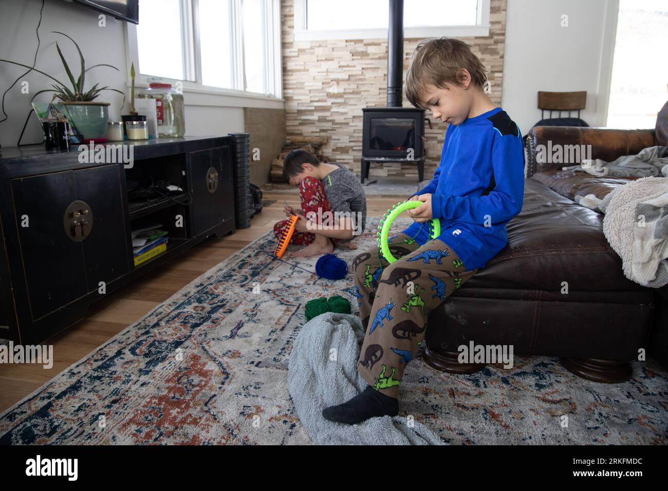 Kleine Jungen lernen, wie man in ihrem Wohnzimmer strickt Stockfoto