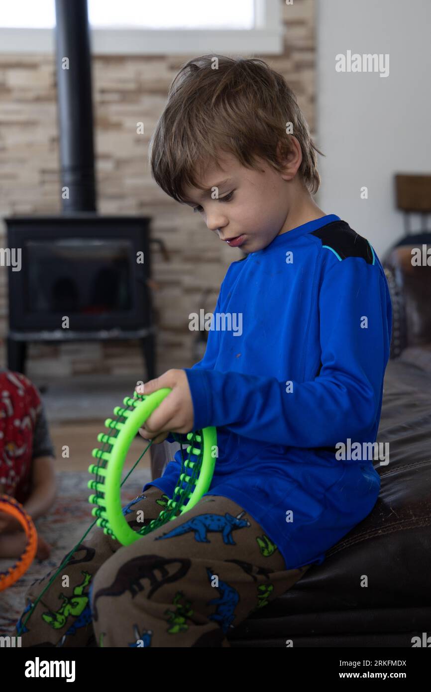 Kind lernt, wie man mit dem Webstuhl strickt Stockfoto