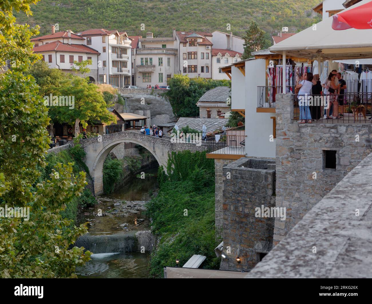 Touristen sehen von erhöhtem Aussichtspunkt über eine kleine Brücke auf dem Fluss Neretva in der Stadt Mostar, Bosnien und Herzegowina, 20. August 2023. Stockfoto