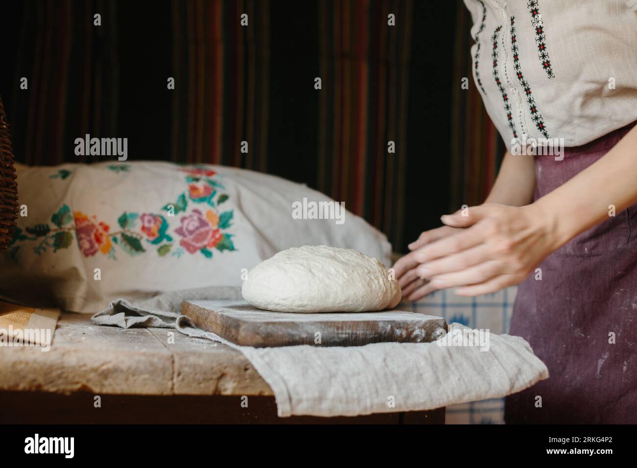 Eine Frau in der ukrainischen Nationalstickerei knetscht Teig für Brot. Stockfoto