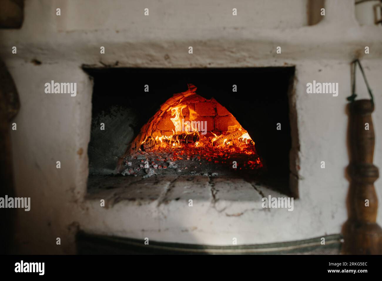 Ukrainischer traditioneller Ofen im Haus. Brennholz brennt im Ofen, Vorbereitung zum Brotbacken. Stockfoto