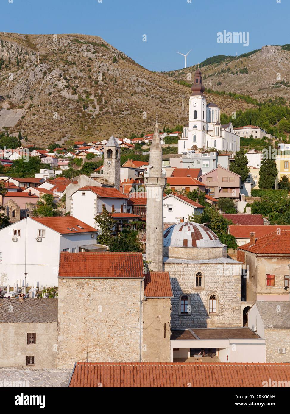 Altstadt in Mostar, Bosnien und Herzegowina, Häuser mit roten Dächern und eine Moschee mit Berg dahinter. August 2023. Stockfoto