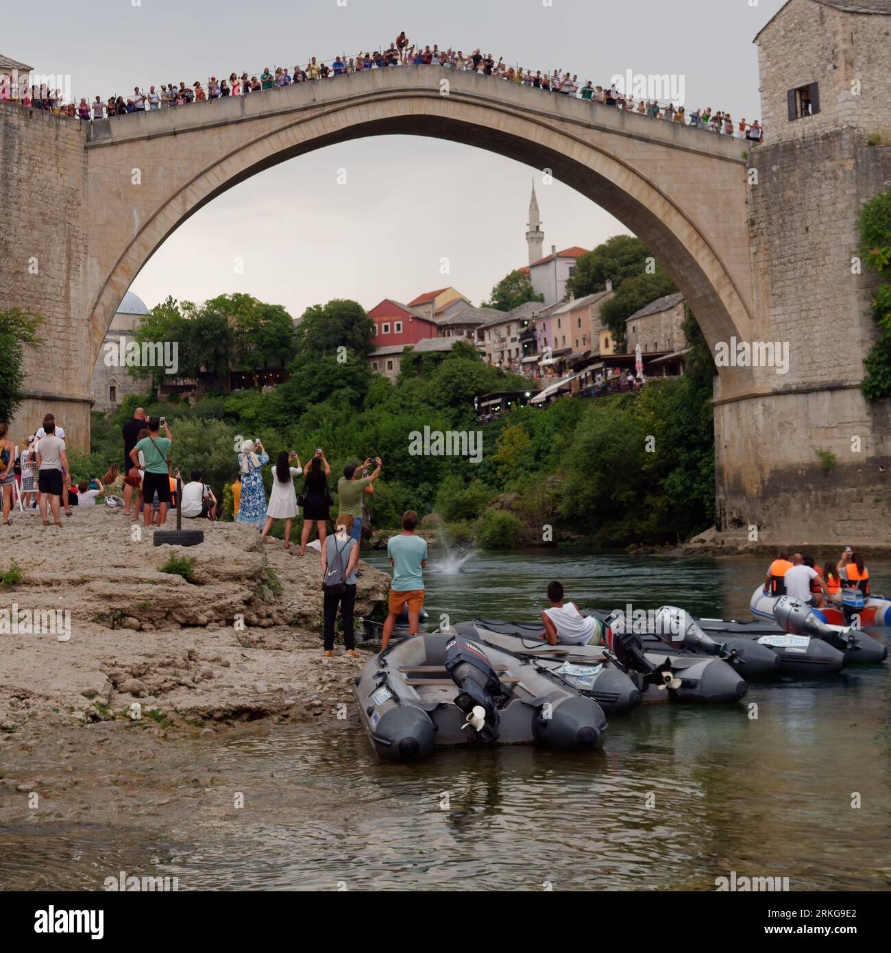 Die Menschen beobachten, wie ein Brückenspringer von Stari Most (Alte Brücke) am 23. August 2023 in Mostar, Bosnien und Herzegowina, auf das Wasser trifft. Stockfoto