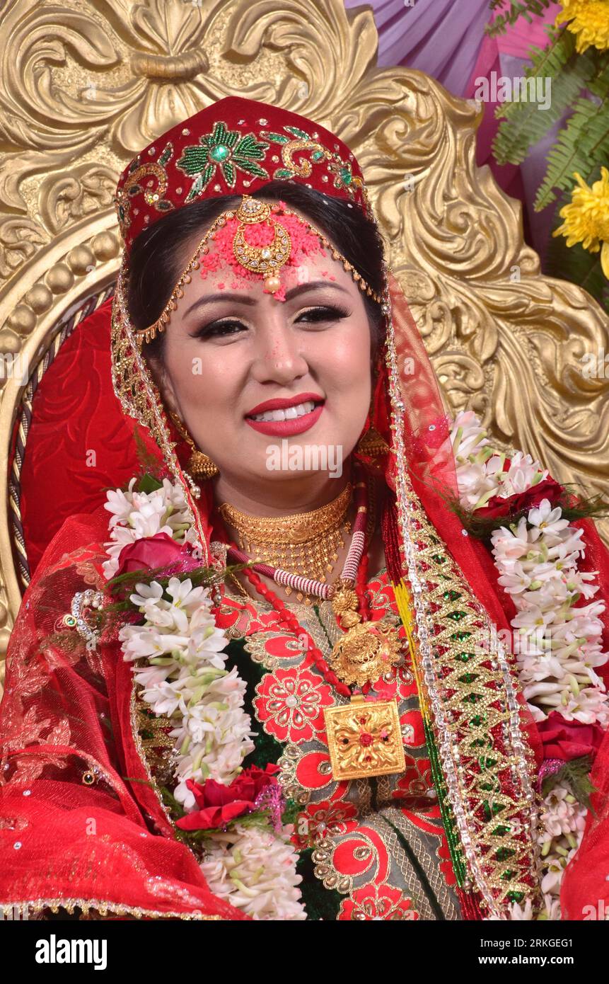Eine fröhliche, lächelnde nepalesische Braut, die ein rotes Saree und Goldschmuck trägt. Stockfoto