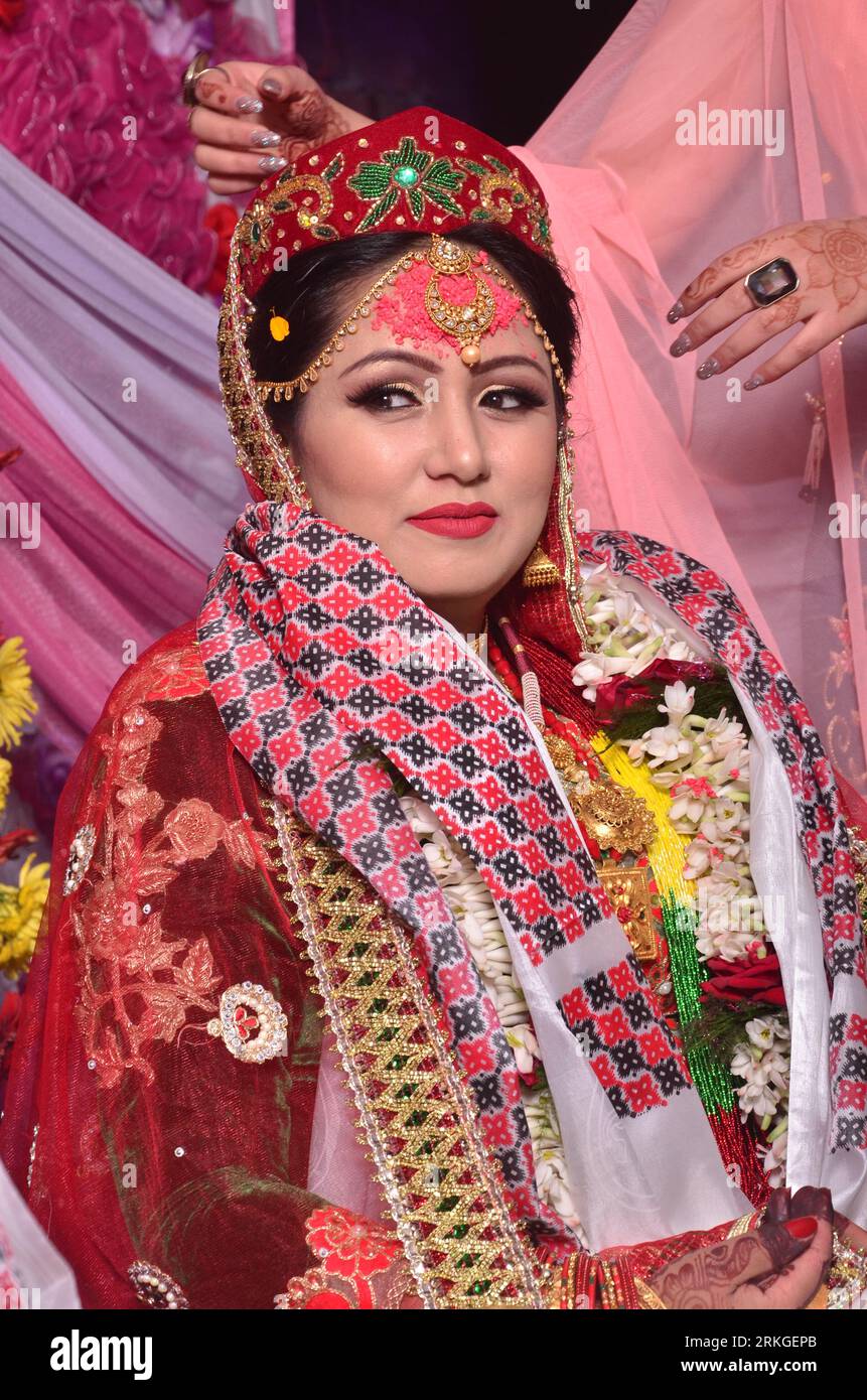 Eine fröhliche, lächelnde nepalesische Braut, die ein rotes Saree und Goldschmuck trägt. Stockfoto