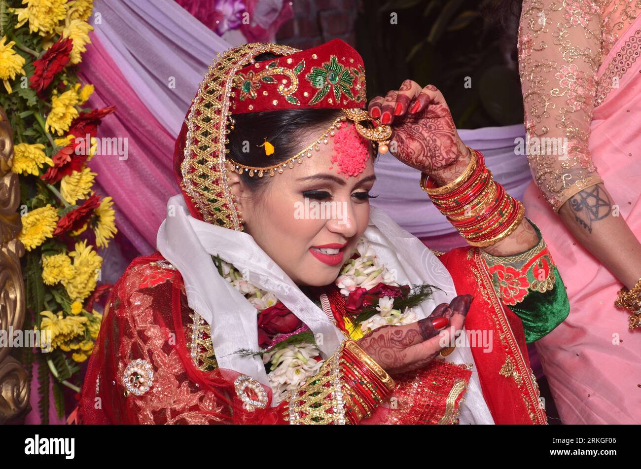 Eine fröhliche, lächelnde nepalesische Braut, die ein rotes Saree und Goldschmuck trägt. Stockfoto