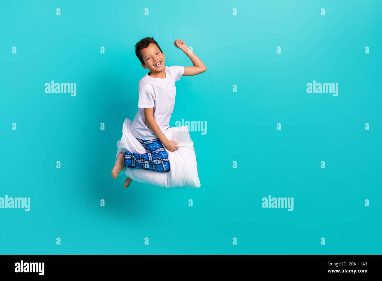 Großes Profilporträt eines verrückten, unbeschwerten Schulkindes, das die Faust aufhebt, fliegendes Kissen, leerer Raum isoliert auf türkisfarbenem Hintergrund Stockfoto