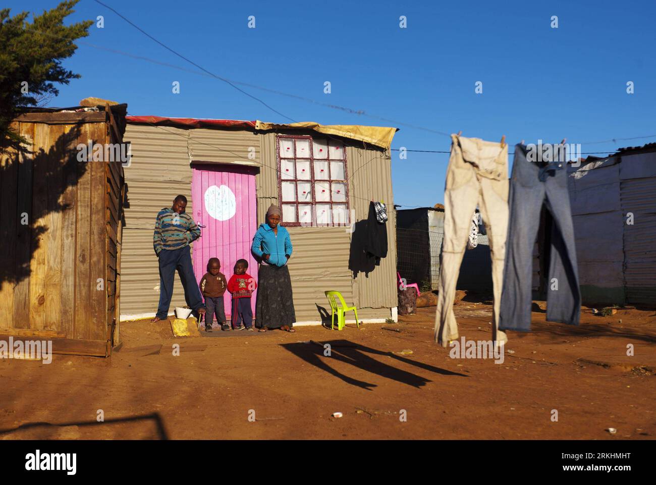 Bildnummer: 55868412 Datum: 24.08.2011 Copyright: imago/Xinhua (110831) -- JOHANNESBURG, 31. August 2011 (Xinhua) -- Pamela Nudwana und ihre Kinder stehen vor ihrem Eisenblechhaus in der Motswaledi-Siedlung in Soweto, Johannesburg, Südafrika, 24. August 2011. Eine der häufigsten Landschaften in Johannesburg und sogar ganz Südafrika ist Slum, von denen einige kilometerlang sind und von Hunderten und Tausenden von Menschen bevölkert werden. Für die meisten Bewohner werden ihre Häuser aus Schrott wie Holzpfähnen oder Wellblech hergestellt. Obwohl er in einem s lebt Stockfoto