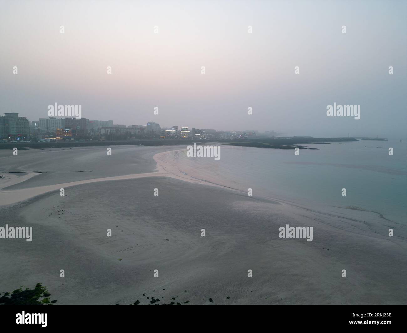 A breathtaking view of a stunning ocean landscape featuring numerous buildings in the backdrop: Jeju, South Korea Stockfoto