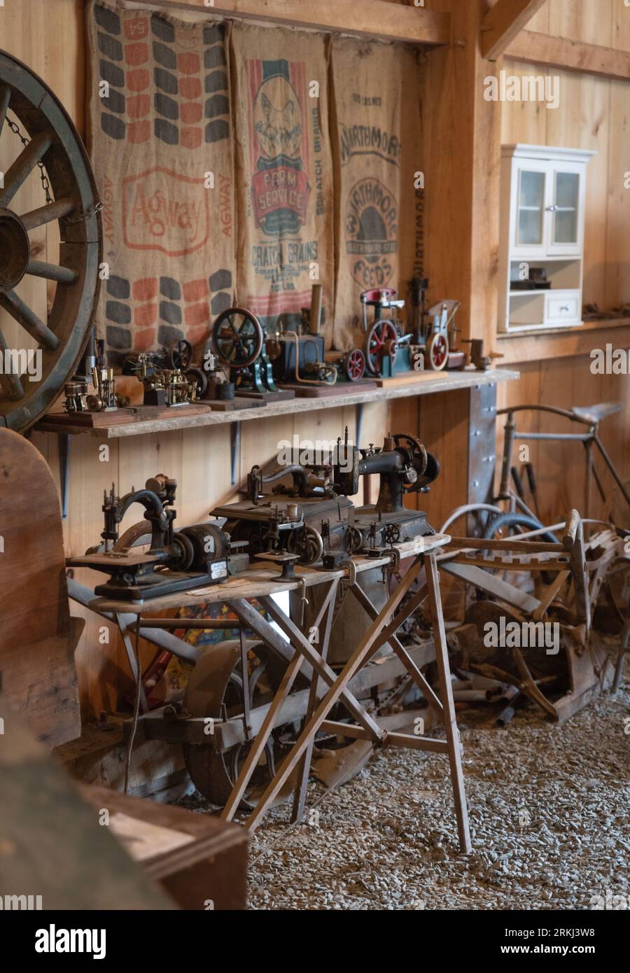 Verschiedene altmodische Nähmaschinen und Antiquitäten in einer rustikalen Holzscheune in Neuengland Stockfoto