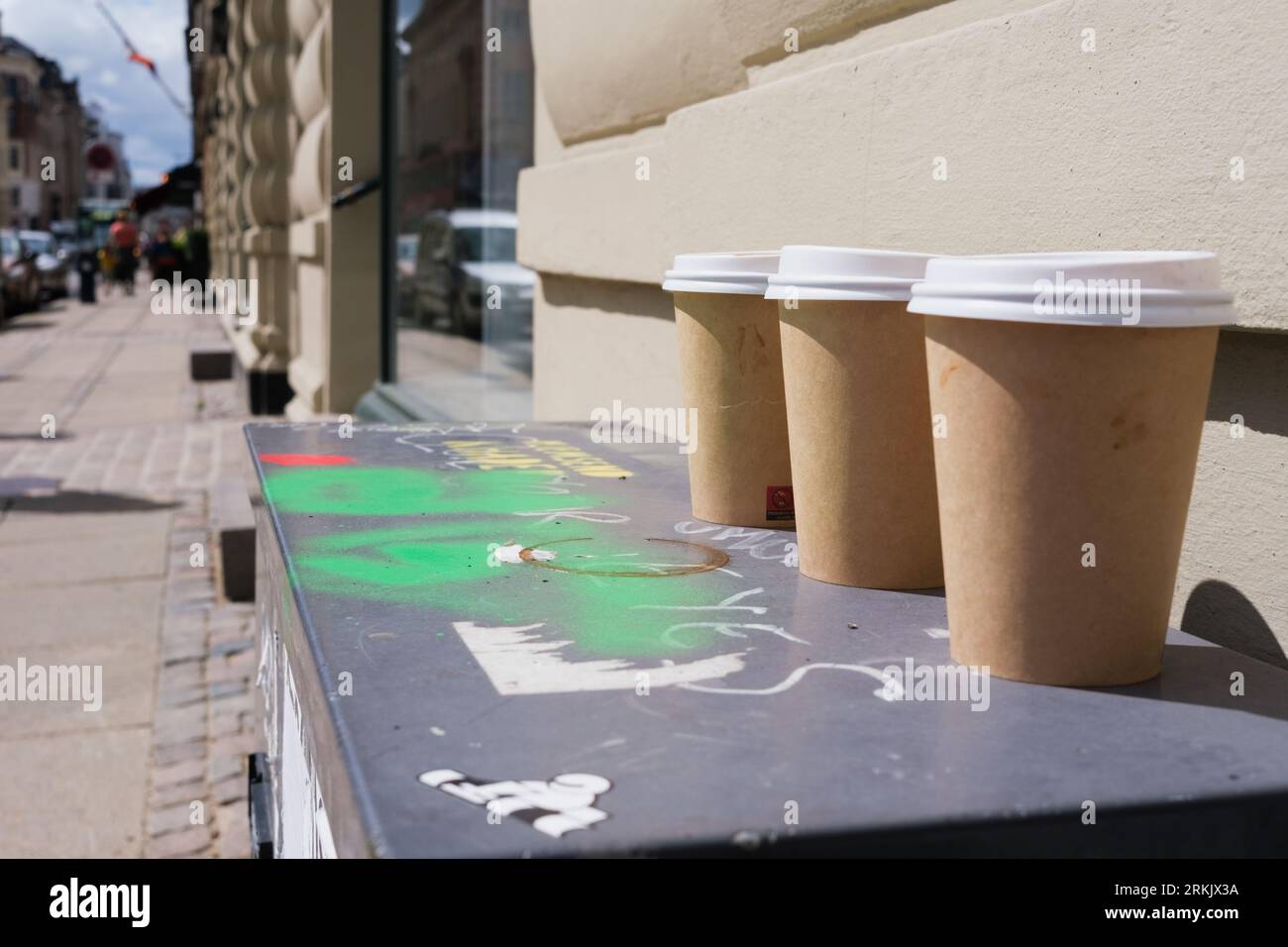 Pappbecher mit heißen Getränken, die auf der Straße ohne Recycling aufgegeben werden. Stockfoto