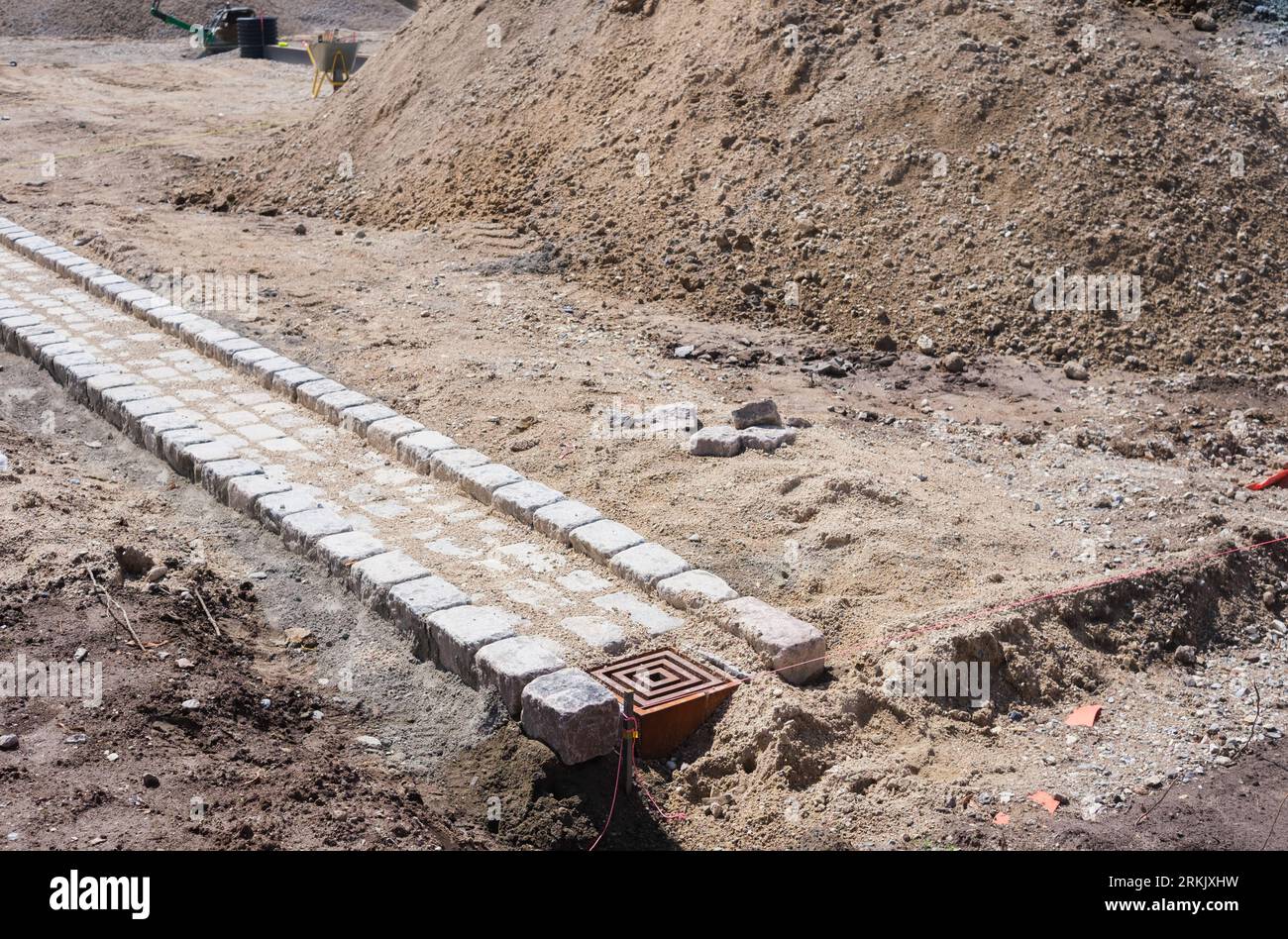 Restaurierungsarbeiten für den Straßenbelag, die einen Kanal für die Entwässerung von Regenwasser in Stein schaffen. Stockfoto