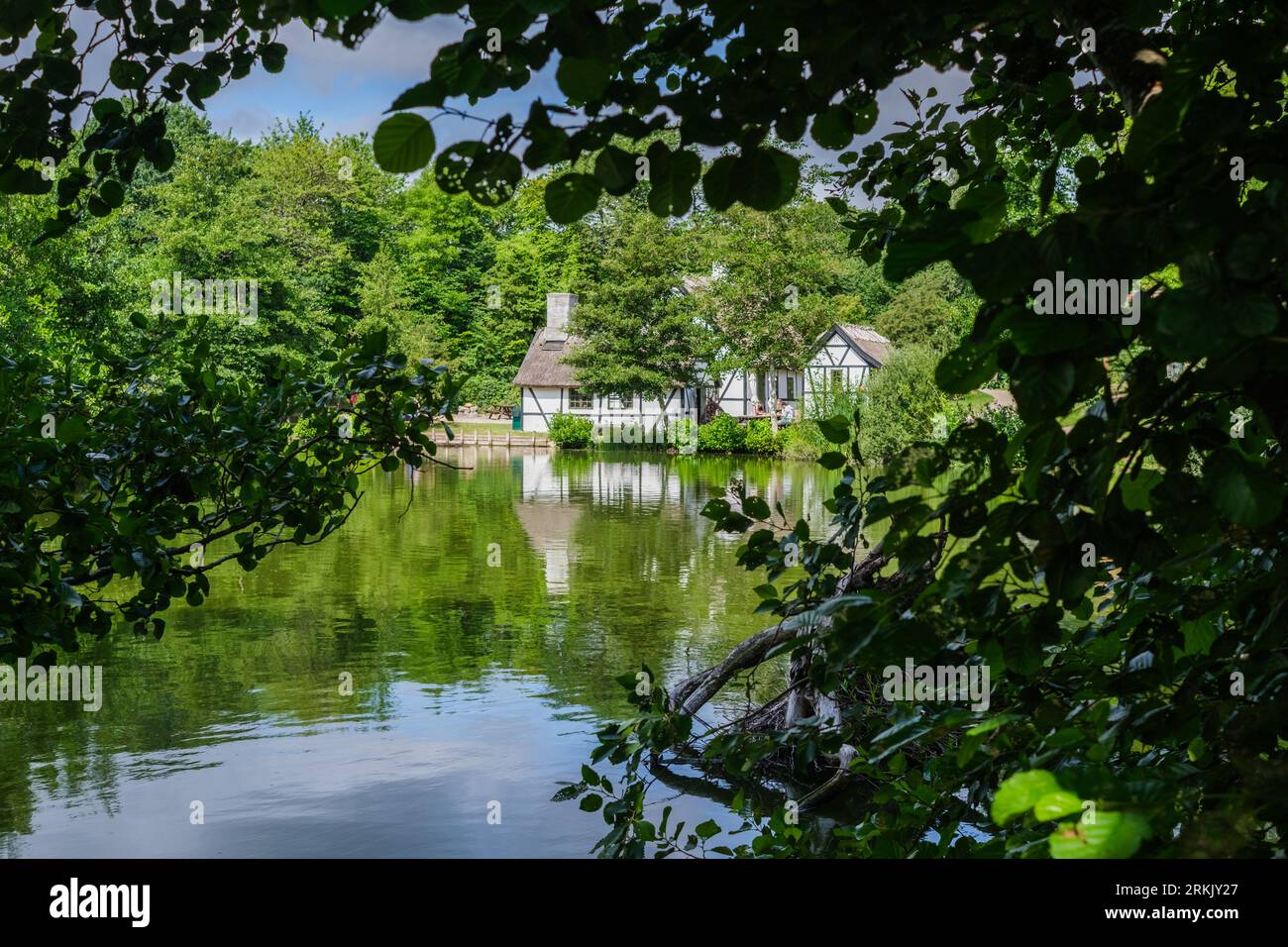 Schönes und ansprechendes Ferienhaus an einem See, durch Baumblätter gesehen. Stockfoto