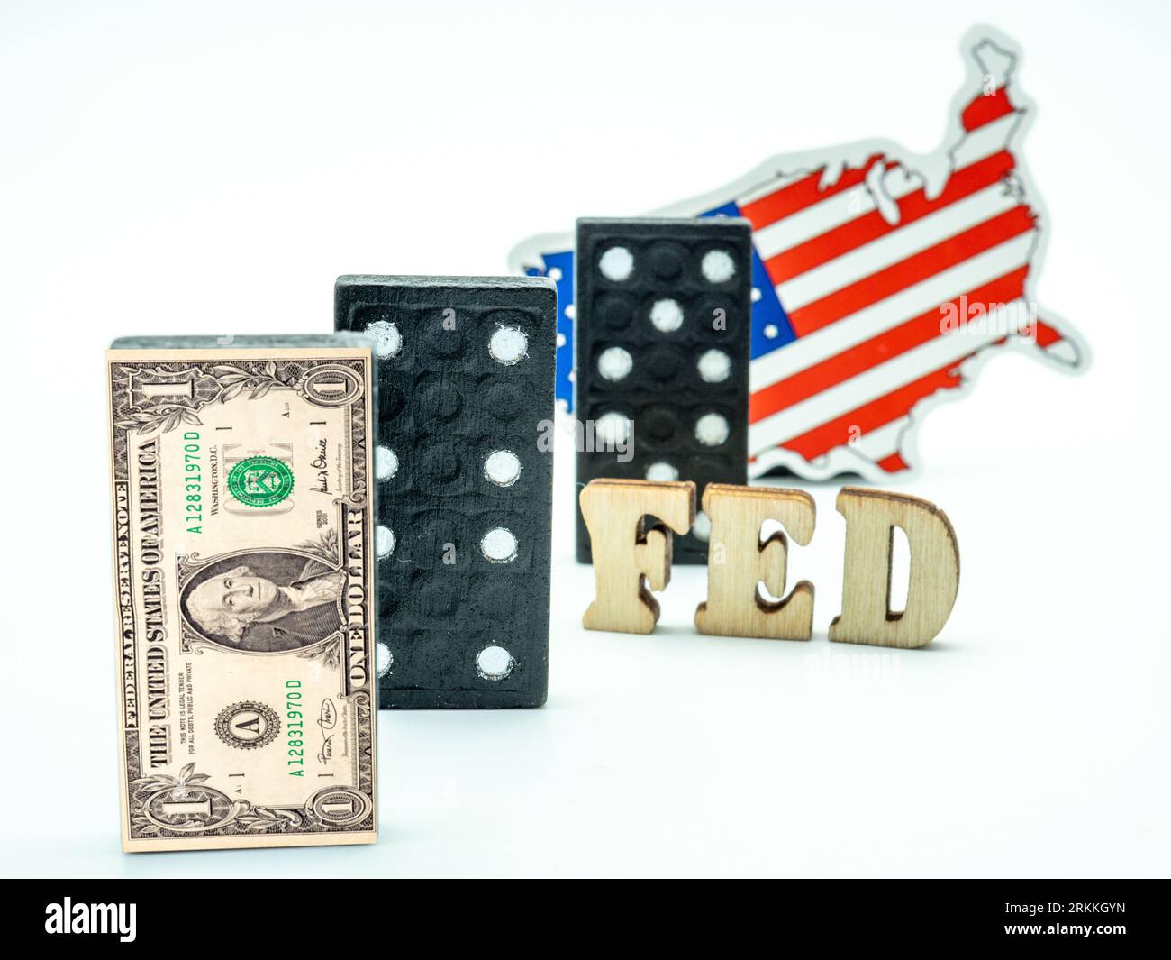 Dollar-Banknote auf Dominosteinen mit eingefügtem Dominostück und US-Flagge auf weißem Hintergrund, Konzept der Finanzkrise Stockfoto