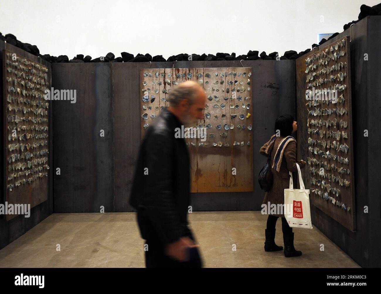 (111118) -- BEIJING, Nov. 18, 2011 (Xinhua) -- Visitors view an exhibit made with porcelain pieces at Translating China -- Solo Exhibition of Jannis Kounellis in Beijing, capital of China, Nov. 18, 2011. The installation exhibition Translating China -- Solo Exhibition of Jannis Kounellis kicked off in Beijing on Friday. This exhibition witnesses the whole new works by Jannis Kounellis, the famous Arte Povera master from Italy. Artists of Arte Povera often use junks and everyday materials as the media of their artworks. (Xinhua/Jin Liangkuai) (zgp) CHINA-BEIJING-JANNIS KOUNELLIS-EXHIBITION (CN) Stockfoto