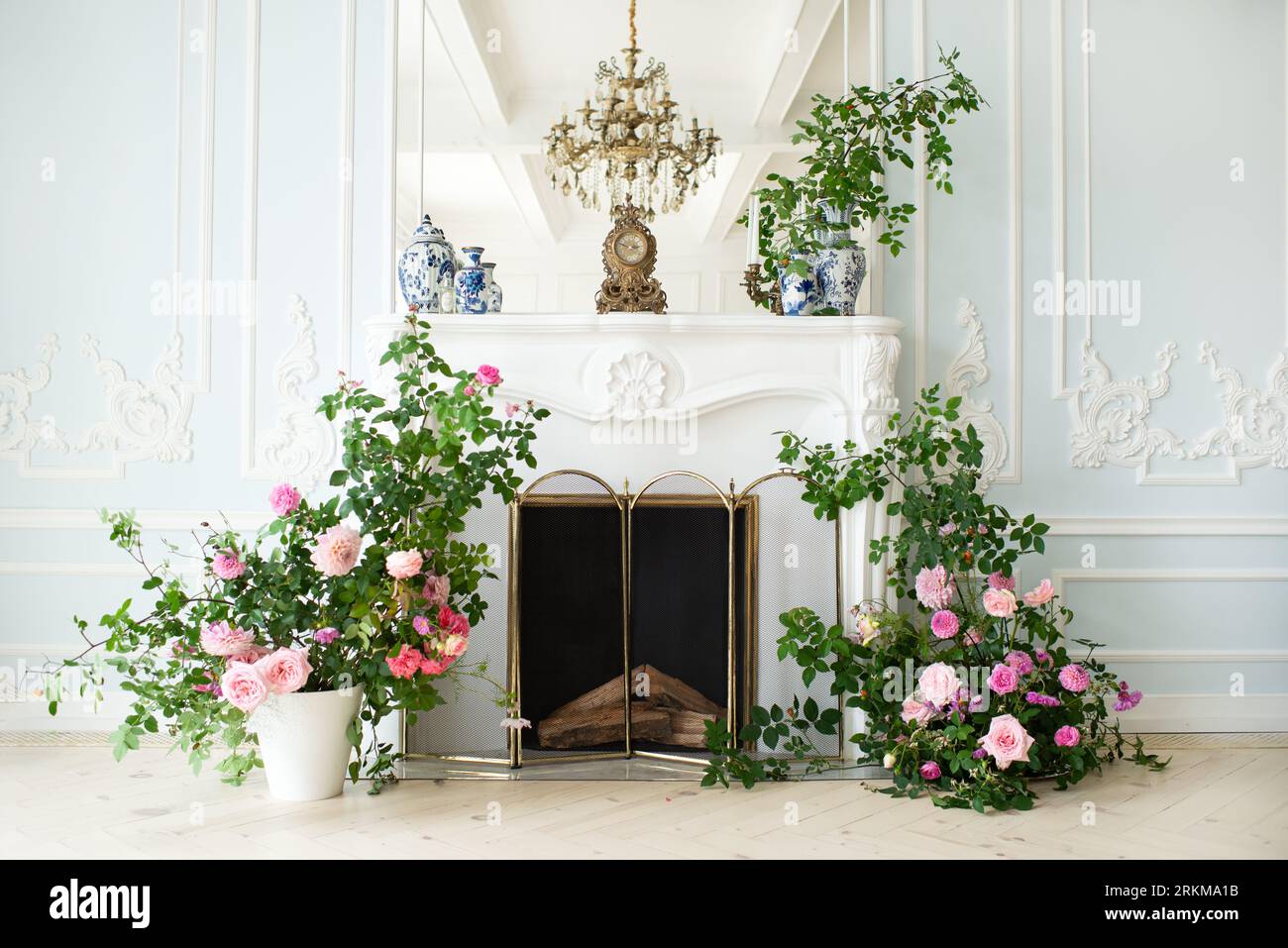 Helles, luxuriöses Wohnzimmer in weiß und Blau mit Blumen in Vasen. Die Wände sind mit Rokoko dekoriert. Vase mit Blumen auf dem Backgro Stockfoto