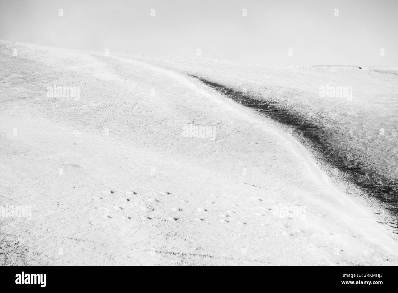 Minimalistischer, fast leerer Blick auf den Schnee in den Bergen, mit einigen kaum sichtbaren Fußabdrücken Stockfoto