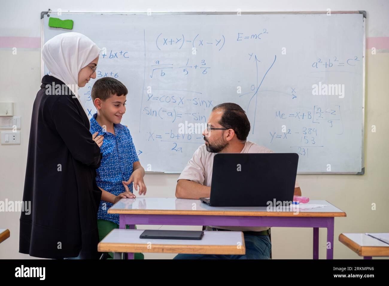 Mutter, die mit dem Lehrer in der Schule über den akademischen Fortschritt des Sohnes spricht Stockfoto