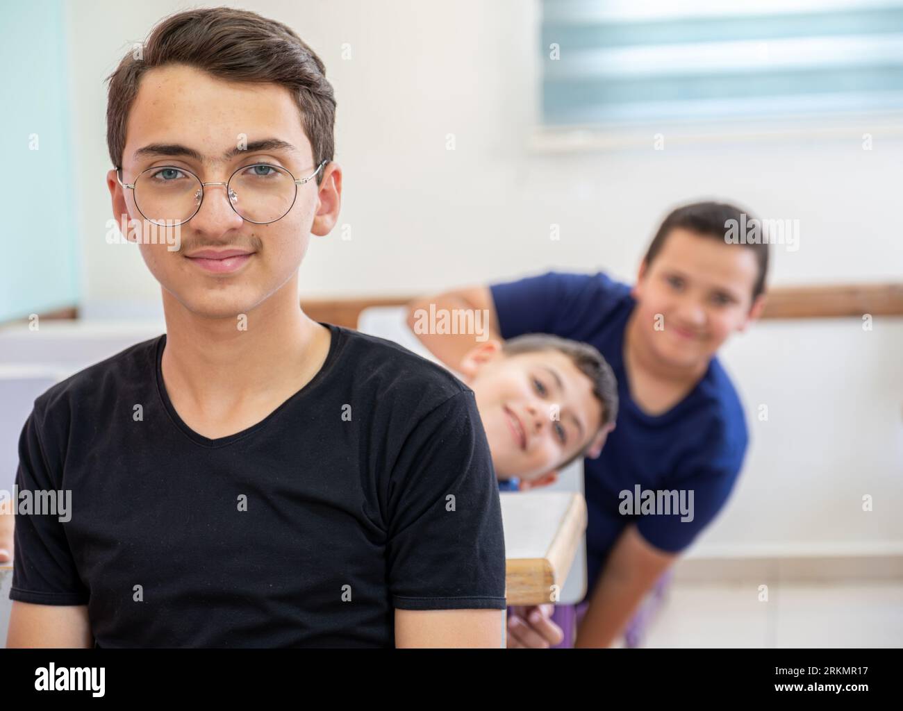 Die Schulkinder, die stehen, bebeißen sich gegenseitig, während sie lächeln Stockfoto