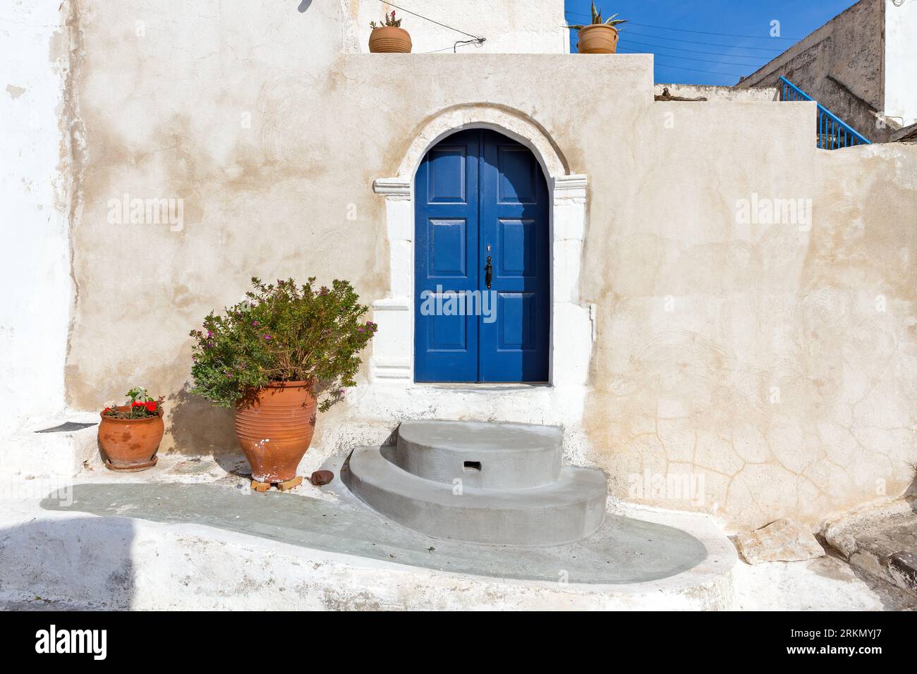 Traditionelles altes Haus mit blauer Tür, ockerfarbenen Wänden und Steinschwelle mit einem Topf mit Pflanzen, in Pyrgos Dorf der Insel Santorin, Griechenland, Europa. Stockfoto