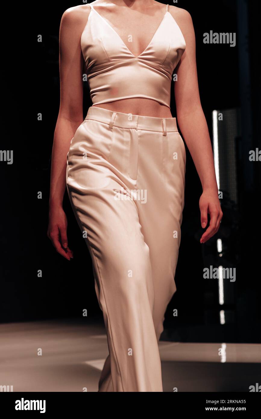 Figur eines Models Frau trägt ein beige elegantes, kurzes Seidenoberteil und eine elegante lange Hose. Modische, stylische Aufnahme. Kleidungskonzept im Straßenstil Stockfoto
