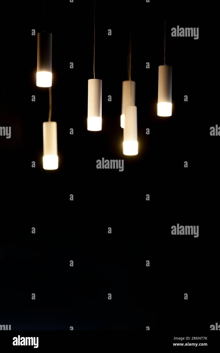 Hängende dekorative Lampen auf dunklem Hintergrund. Dekoratives Beleuchtungskonzept. Schwarzer Hintergrund, Kopierbereich. Stockfoto