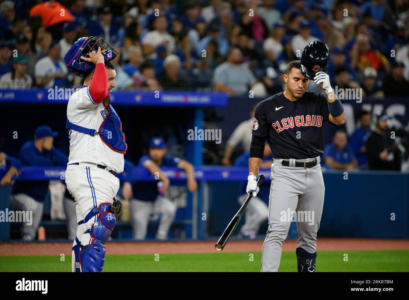 Cleveland Guardians' Ramon Laureano, right,and Toronto Blue Jays catcher Alejandro Kirk, left, adjust their helmets during the sixth inning of a baseball game in Toronto, Friday, Aug. 25, 2023. (Christopher Katsarov/The Canadian Press via AP) Stockfoto