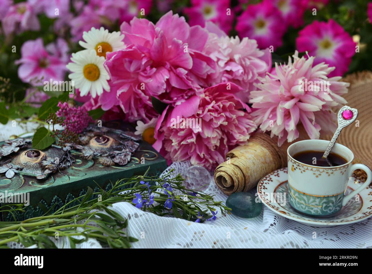 Wunderschönes Stillleben mit Pfingstrosenblüten, dekoriertem Buch und Teetasse auf dem Tisch. Romantische Grußkarte zum Geburtstag, Valentinstag, Muttertag Konzept Stockfoto