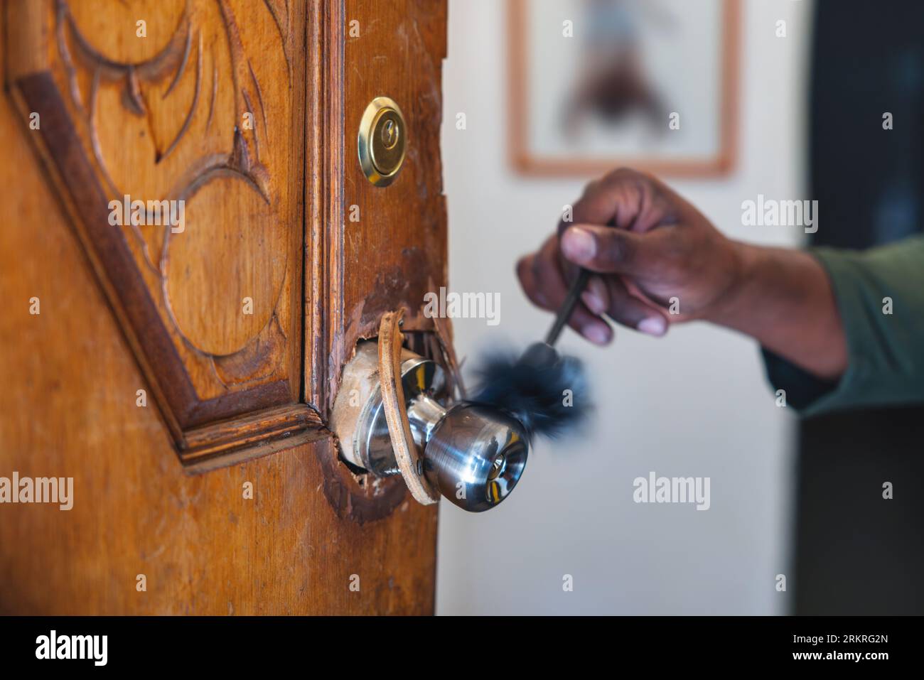 afroamerikanischer Detektiv, der forensische Beweise für Fingerabdrücke mit einer Bürste sammelt, die den kaputten Türgriff abstaubt. Stockfoto