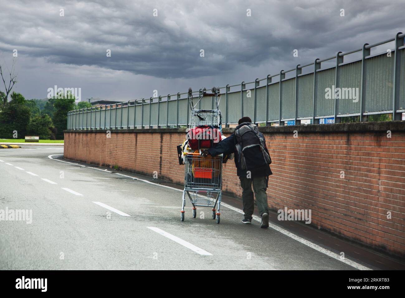 Obdachlose schiebt den Einkaufswagen auf die Straße Stockfoto